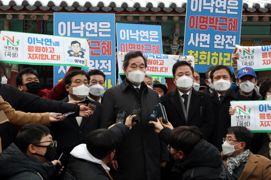 이낙연 민주당 대표가 18일 광주 북구 운정동 국립 5·18민주묘지에서 참배를 마친 뒤 기자들 질문에 답하고 있다. 이 대표 주변에는 전직 대통령 사면에 반대하는 광주시민들과 이 대표를 응원하는 지지자들이 각각 손팻말을 들고 있다. 연합뉴스